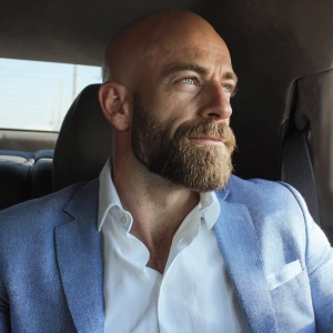 Refine the appearance of a bald man with a beard, sitting in a c...