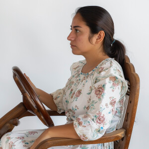 A cute Mexican woman sitting in a wooden chair
Brown ponytail...