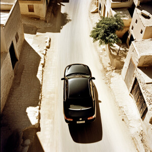 Aerial shot from above of a car driving down the street of an Ar...