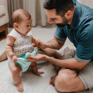 A one year old baby girl getting her poopy diaper change by dadd...
