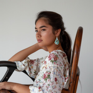 A cute Mexican woman sitting in a wooden chair
Brown ponytail...