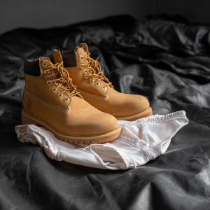Make a pair of tan men’s work boots and on top of them a white j...