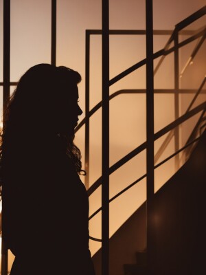 A woman with long hair dressed in a man suit walking down a stai...