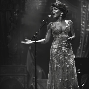 A black transgender woman in a beautiful dress singing on a stag...