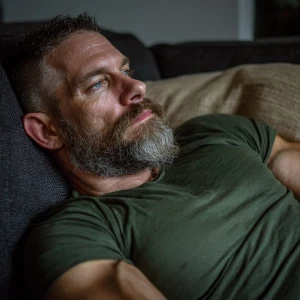 The image shows a muscular bodybuilder man lying on a couch, app...