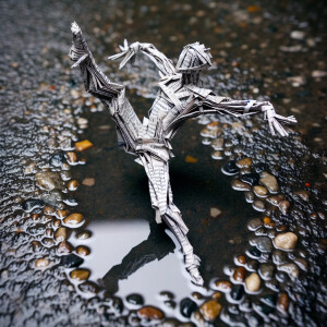 Create an image of a figure made from folded newspaper, posed in...