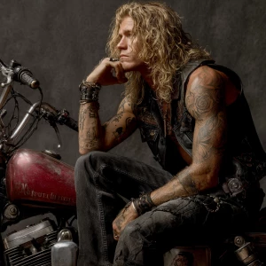 The image shows a muscular bodybuilder man with a tattooed arm s...