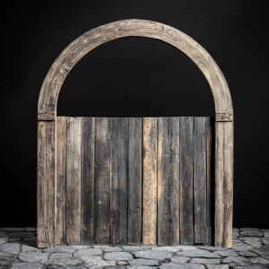 A wooden archway, centered in the image. The arch is made from beautiful vintage barndoor wood.   The archway has a smooth, semi-circular shape and shows the nails and slight wear of the weathered barn wood.  The wood has a grey, beige weathered color with lighter, streaky highlights.  The interior of the archway is completely black. The archway sits atop a natural vintage cobble stones. The background is a plain,black.The overall style is rustic, minimalist, and natural, evoking a sense of warmth and organic beauty. The lighting is even, casting no distinct shadows within the image, which enhances the focus on the wood texture and its details. The perspective is straight-on, looking directly at the archway.