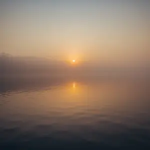 Calm lake at sunrise, misty light