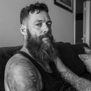 Hey, check out this dude with a beard and tattoos. He's sitting...