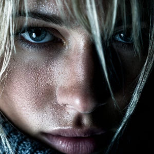 Ultra close-up noir portrait of a determined blonde woman. Her e...