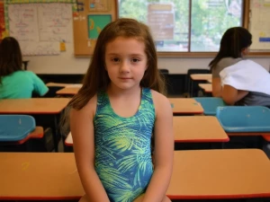 A teenage girl sitting in front of me viibrant swimsuit, middle...