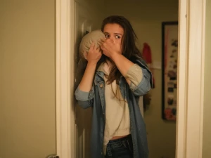 A young woman in casual attire unexpectedly enters a room, looki...