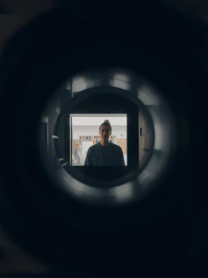 view through the camera lens showing blurred figure in corner