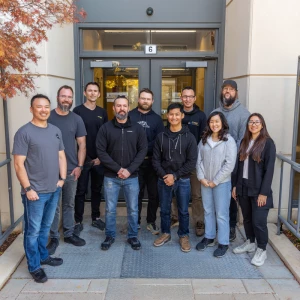 10 employees posing for a picture at the entrance of a company.